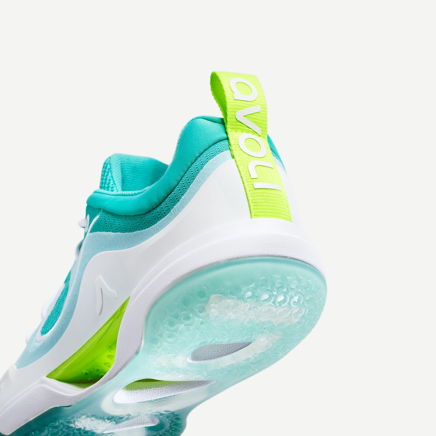 Heel view of a white and green low-top volleyball shoe with reinforced toe protection and superior traction designed for court play.