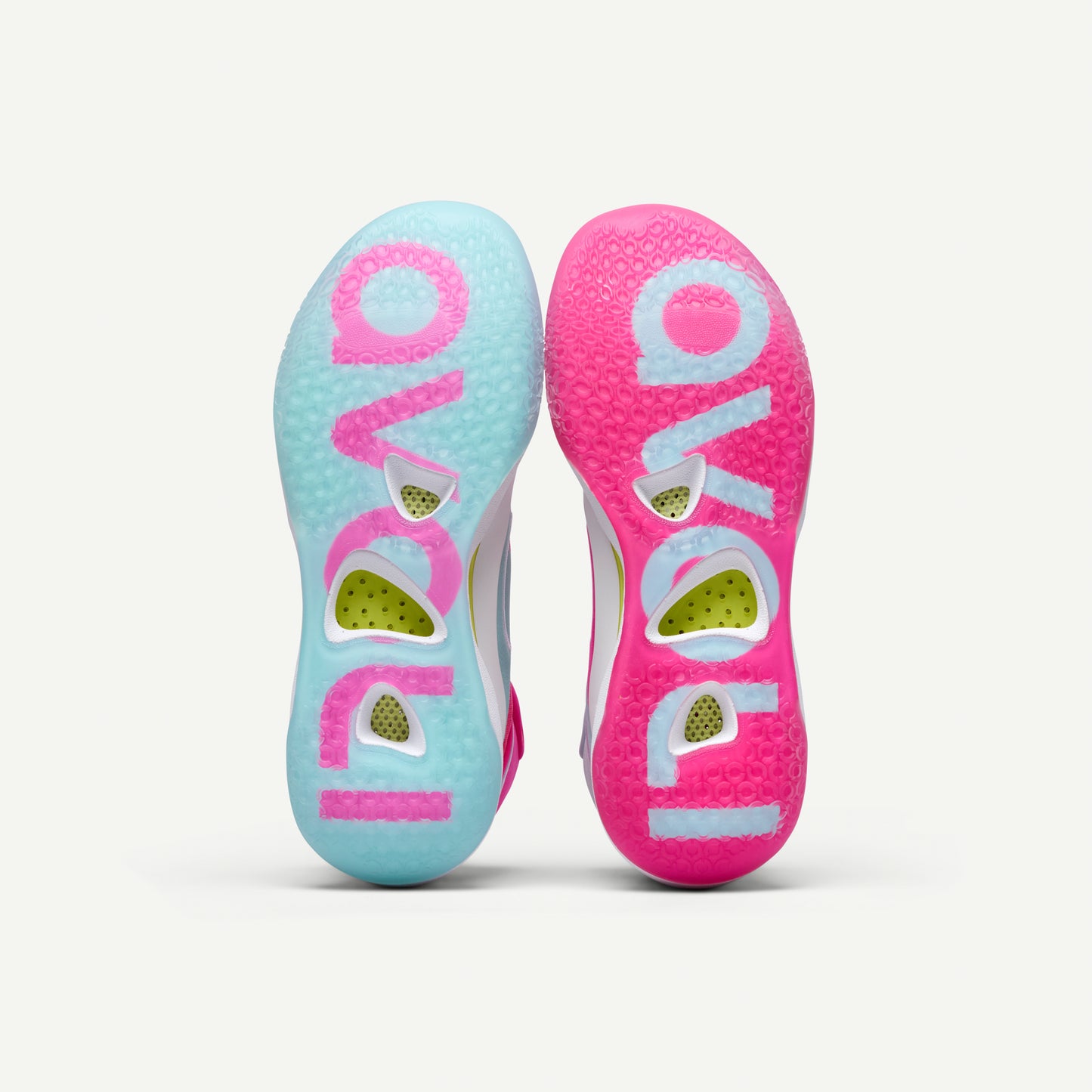 Mismatched pair of pink and light blue mid top volleyball sneakers soles on a white background